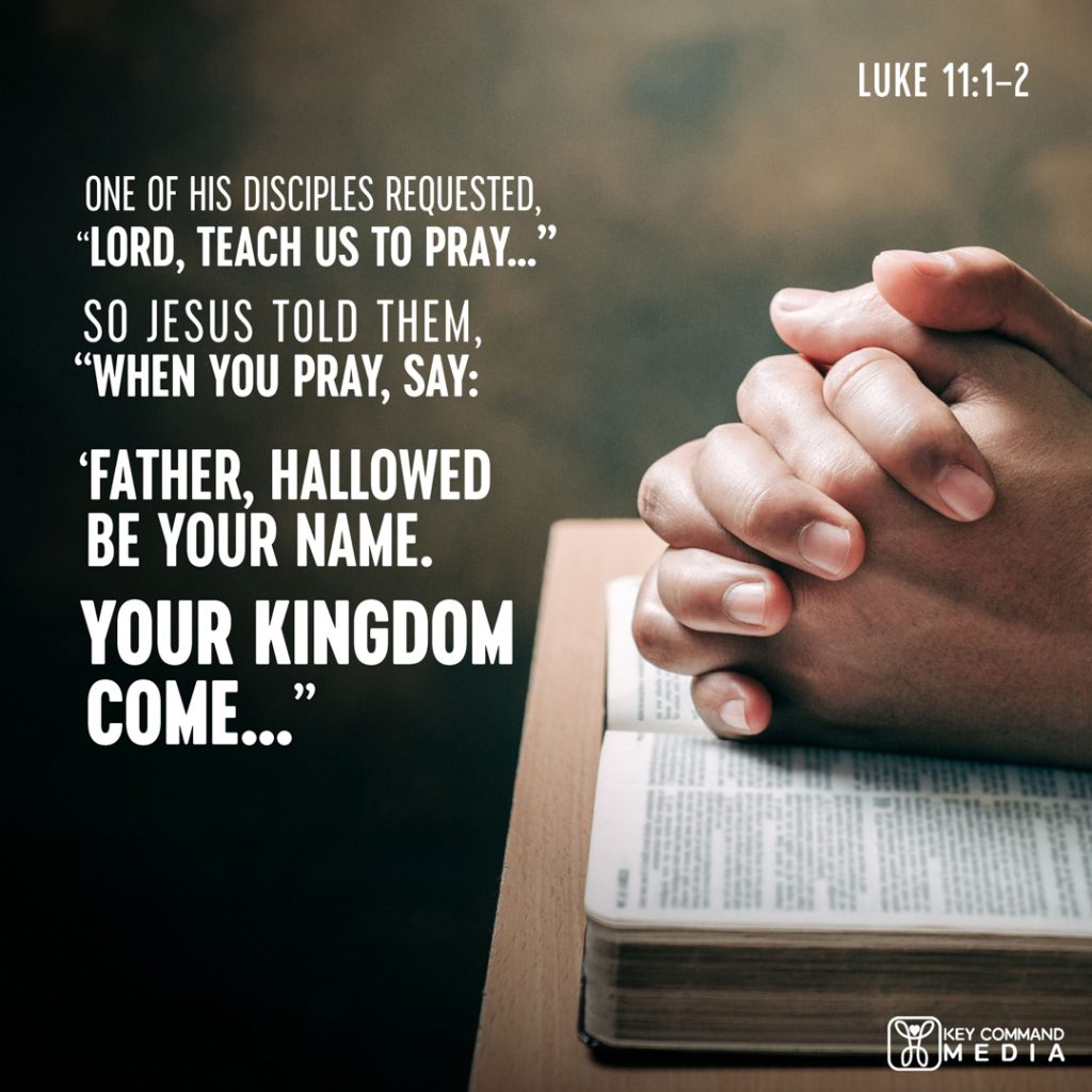 A man's hands are folded on top of an open Bible with Luke 11:1-2, "One of his disciples requested, "Lord teach us to pray..." So Jesus told them, "When you pray, say, 'Father, hallowed by Your name. Your kingdom come..."