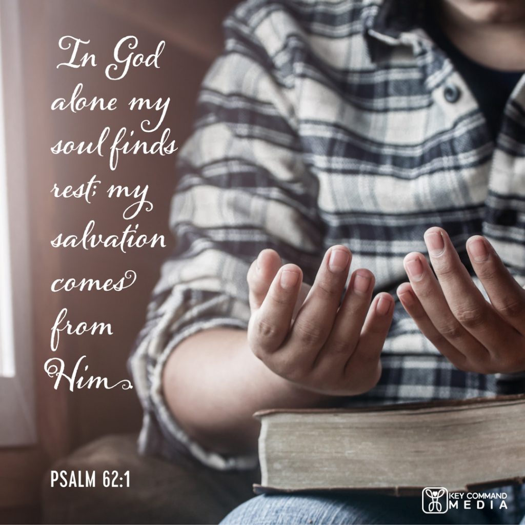 A person sits with hands resting on top of the Bible in their lap, palms facing upwards with Psalm 62:1, "In God alone my soul finds rest; my salvation comes from Him."